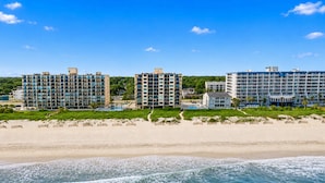 A beachfront hotel with multiple high-rise buildings, a sandy beach, and a clear blue sky.