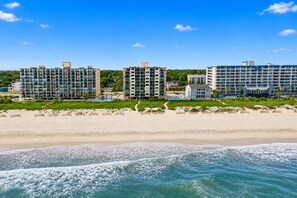 A beachfront hotel with multiple high-rise buildings, a sandy beach, and a clear blue sky. - Spinnaker #304 - Beautiful Oceanfront Condo in North Myrtle Beach (North Myrtle Beach)