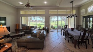 A spacious living room with a fireplace, comfortable seating, and a large dining area with a view of the outdoors. - Luxury Villa Overlooking Lake Jovita's Championship Golf Course (Dade City)