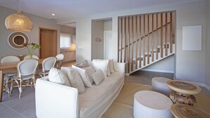 A modern living room with a sofa, chairs, a dining table, and a staircase. - Villa Andrella - Beach Haven (Pointe d'Esny)