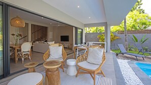 A modern outdoor living area with wicker furniture, a pool, and a view of the interior. - Villa Andrella - Beach Haven (Pointe d'Esny)