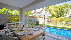 A dining area with a pool view, outdoor furniture, and a barbecue grill. - Villa Andrella - Beach Haven (Pointe d'Esny)
