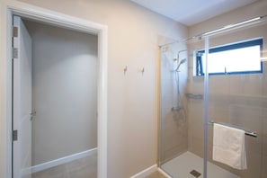 Un baño moderno con cabina de ducha de vidrio, un perchero visible y un ventanal que proporciona luz natural.