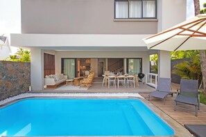A modern house with a swimming pool, outdoor seating, and a patio area.