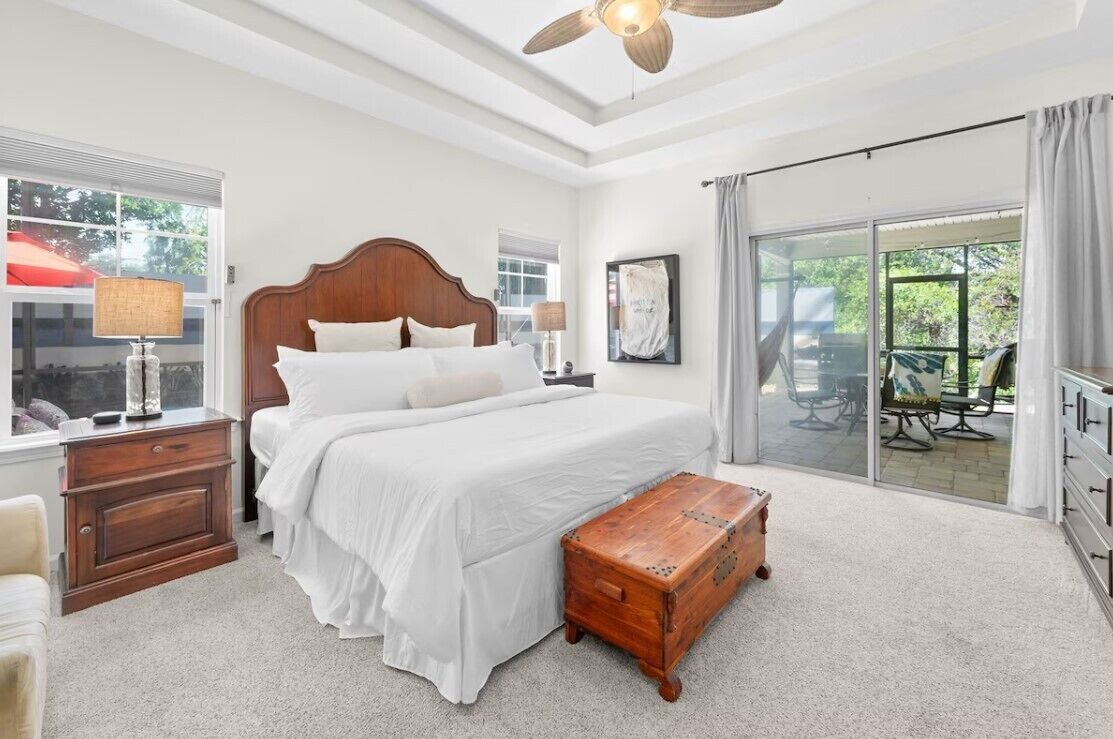 Una camera da letto con un letto grande, un comodino in legno, una lampada, un baule di legno e vista all'esterno tramite una porta scorrevole in vetro.