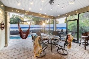 Eine überdachte Terrasse mit Pool, einem Esstisch, Stühlen und einer Hängematte.