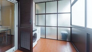 A laundry area with a washing machine, a glass door, and a tiled floor. - Faraglioni Sea View Terrace by Wonderful Italy (Aci Catena)