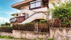 A two-story building with a balcony, a staircase, and a concrete wall. - Faraglioni Sea View Terrace by Wonderful Italy (Aci Catena)