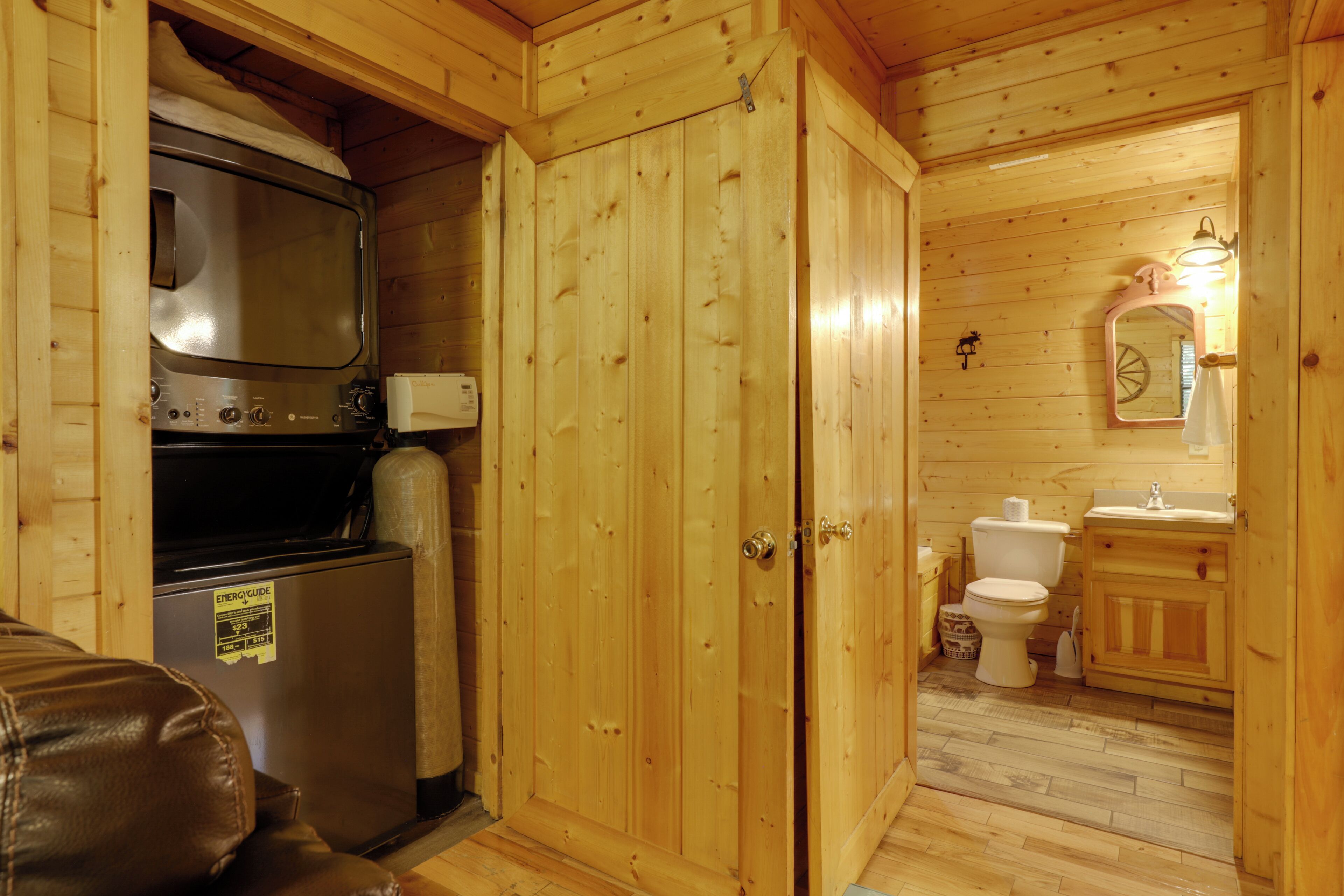 Een knus houten vakantiehuisje met een kitchenette, toilet en wastafel.