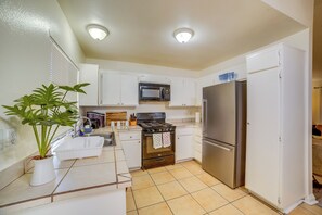 A kitchen with white cabinets, a stainless steel refrigerator, a microwave, and a stove.