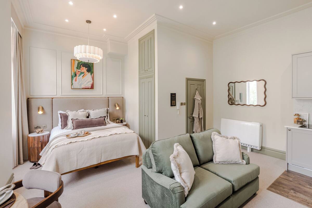 A bedroom with a bed, bedside table, lamp, and a green sofa.