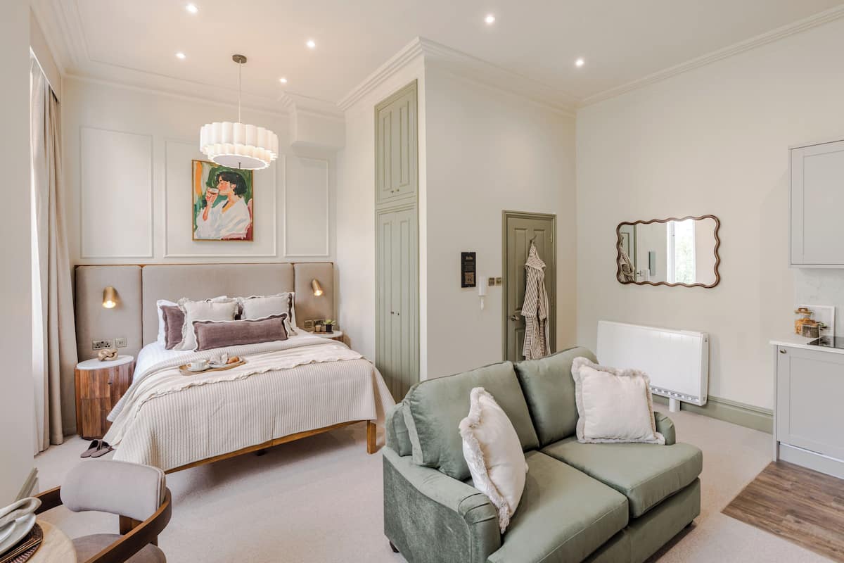 Une chambre à coucher avec un lit, une table de chevet, une lampe et un canapé vert.