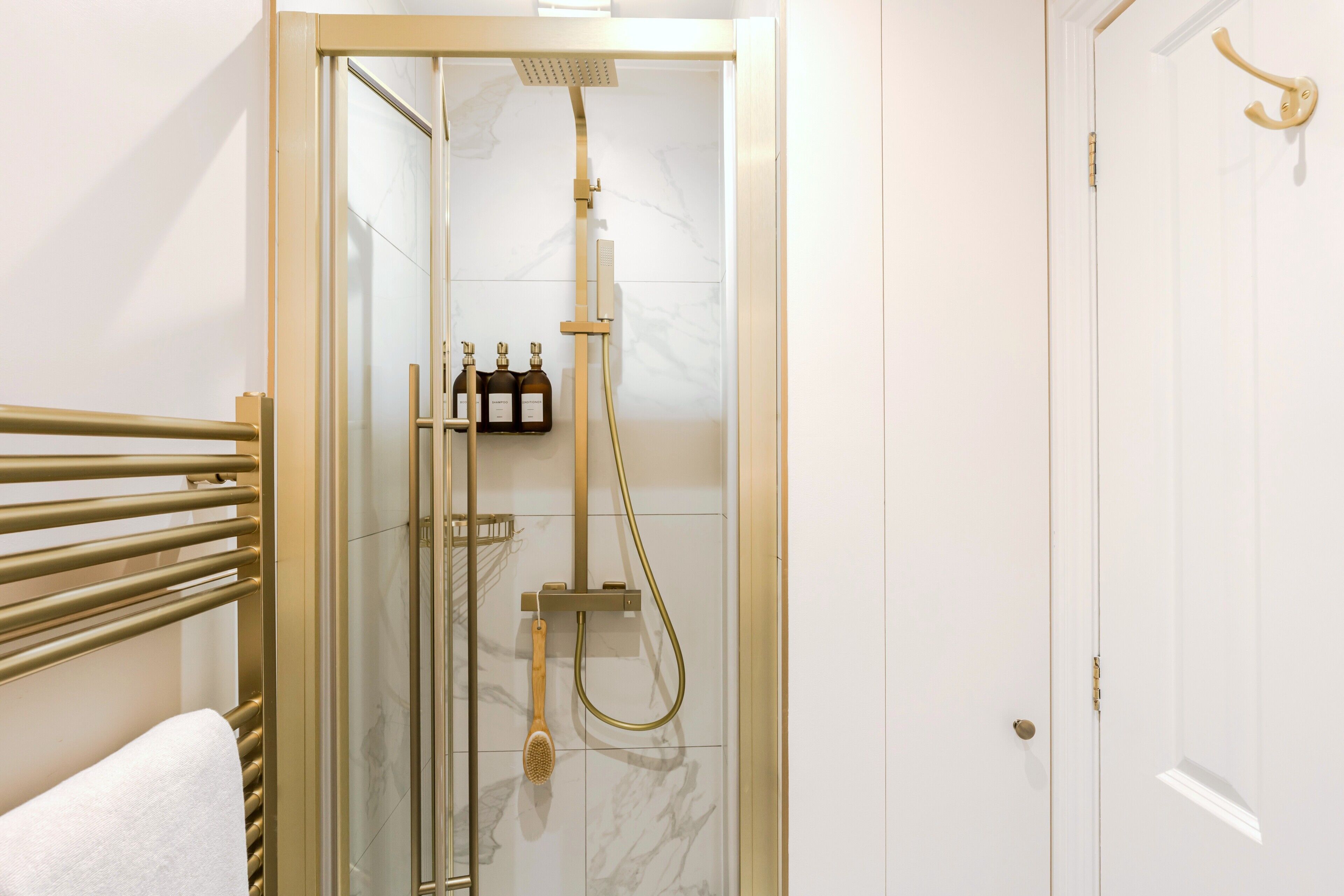 A walk-in shower with a glass door, a towel rack, and a bottle of shampoo.