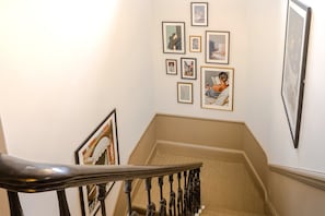 A staircase with a handrail, carpeted steps, and framed pictures on the walls. - Earl's Court - Your Apartment (London)