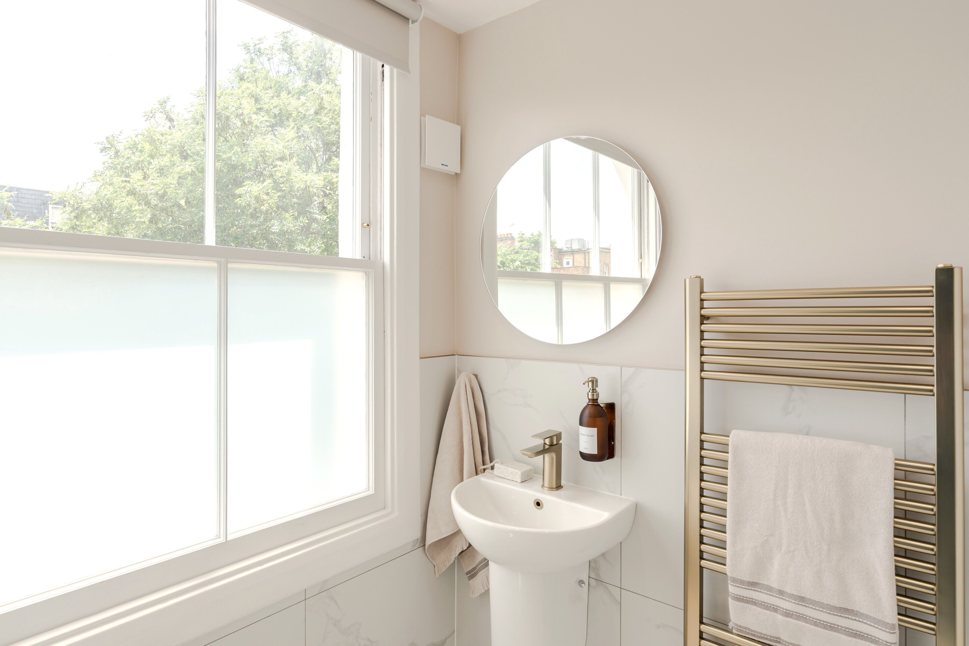 Un baño con una ventana grande, un lavabo, un espejo y un perchero para toallas.
