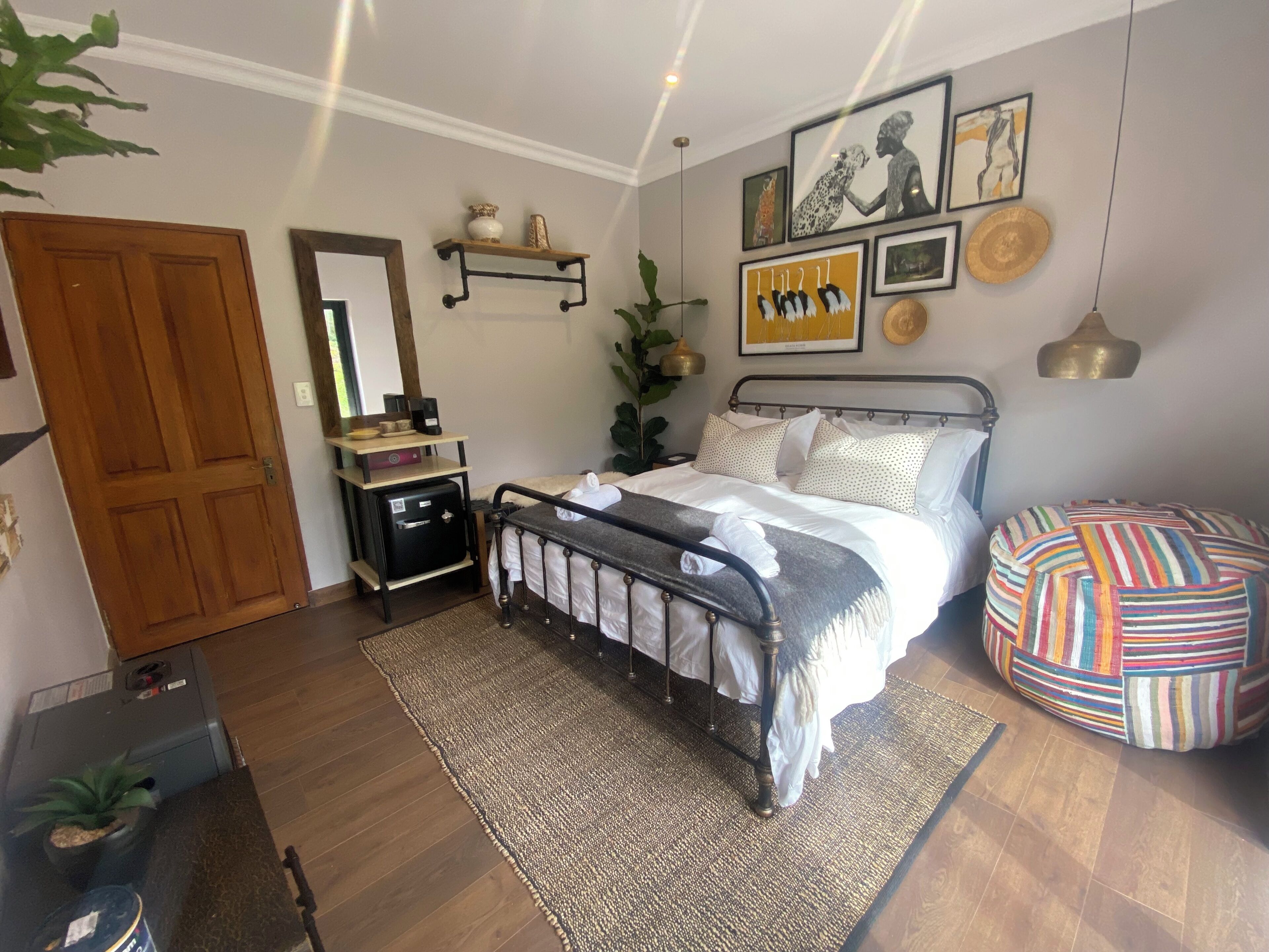 A bedroom with a bed, bedside table, lamp, and a colorful ottoman.