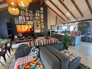 A modern living room with a sofa, a flat-screen TV, and a kitchen in the background. - The Liora (hoekwil)