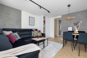 Ein modernes Wohnzimmer mit einer schwarzen Couch, einem Couchtisch und einem Essbereich mit Tisch und Stühlen.