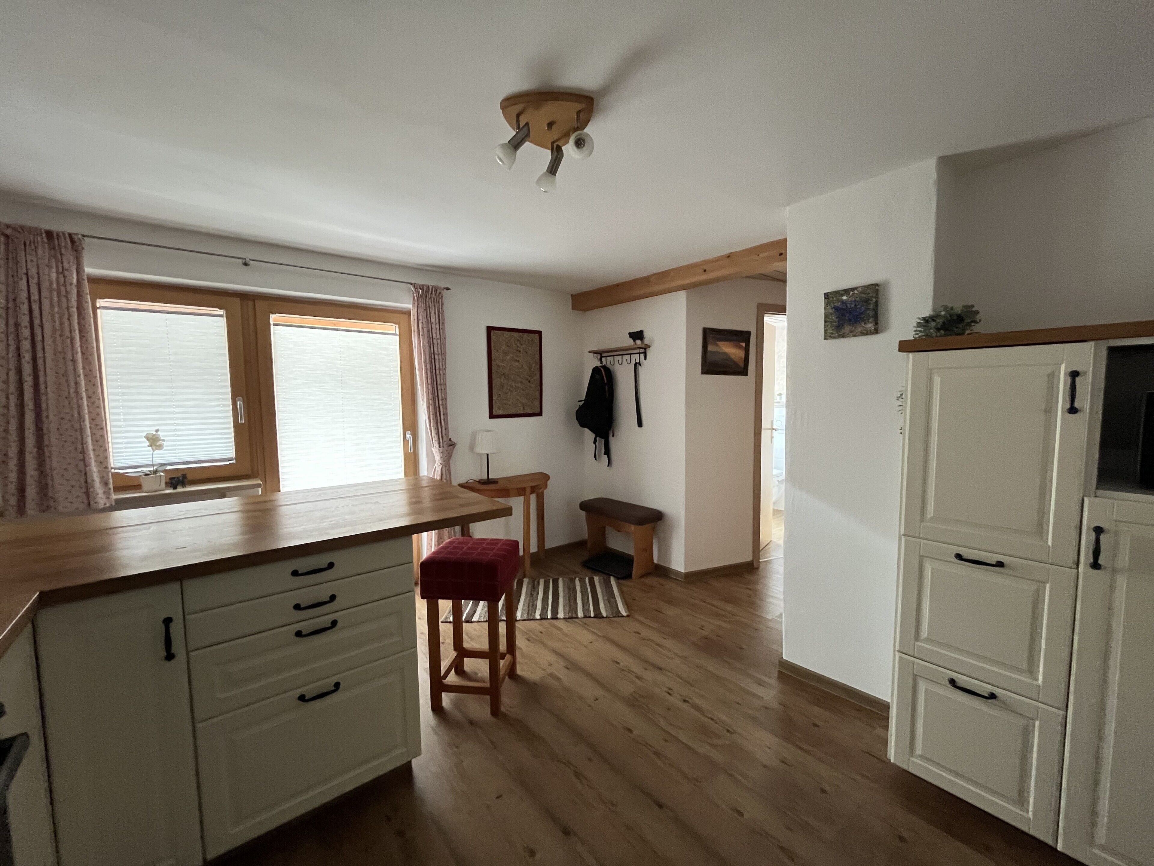 Une cuisine avec des meubles de rangement en bois, un banc, une table et un luminaire suspendu au plafond.