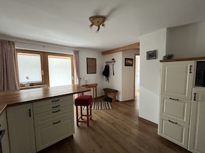 Eine Küche mit Holzausstattung, einer Bank, einem Tisch und einer Deckenleuchte.