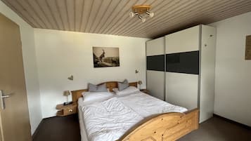 Ein Schlafzimmer mit einem hölzernen Bett, einem Nachttisch, einem Kleiderschrank und einem Deckenventilator.
