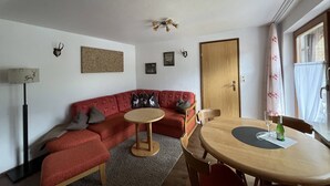 Ein gemütliches Wohnzimmer mit einem roten Sofa, einem runden Holztisch und einem Deckenventilator.