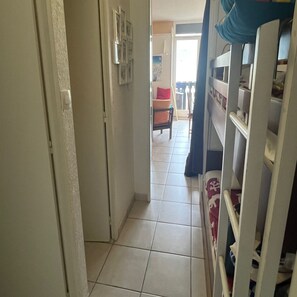 A hallway with a tiled floor leading to a room with a bed and a wardrobe. - Vrbo Property (Saint-Lary-Soulan)