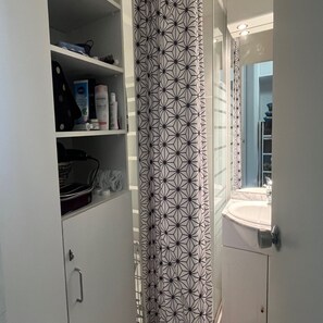 A bathroom with a white sink, a mirror, and a shower curtain with a geometric pattern. - Vrbo Property (Saint-Lary-Soulan)