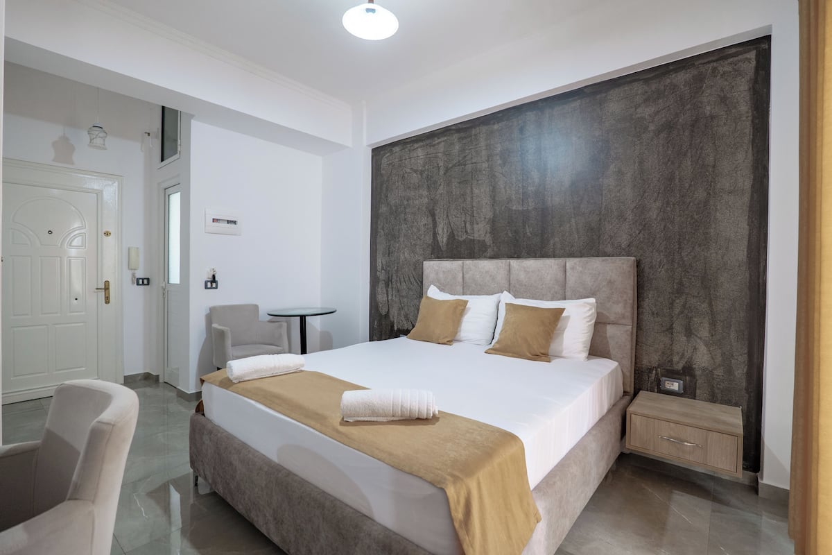 Una habitación de hotel con una cama grande, una mesita de noche, una silla y una pequeña mesa.