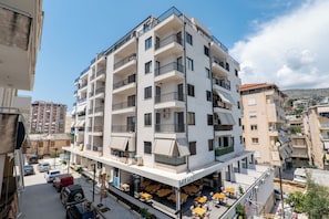 Un edificio a più piani con balconi, zone salotto all'aperto e un ristorante in vista chiamato 'GRACE'.