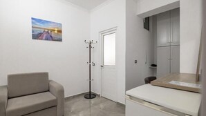 A room with a sofa, a coat rack, a door, a cabinet, and a printer. - Grace Corner  (Sarande)