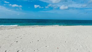 Uma praia com areia branca e céu azul límpido.