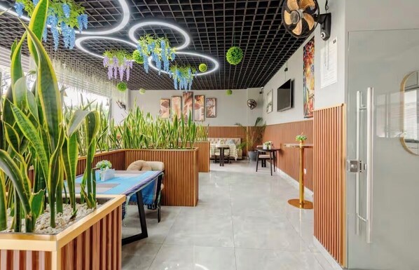 A modern hotel lobby with a high ceiling, wooden paneling, and a central seating area with tables and chairs. - Spacious Fully-stocked modern studio with a gym, cafe, & pitch in Kileleshwa (Nairobi)