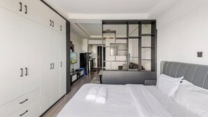 A modern hotel room with a large bed, a wardrobe, a desk, and a seating area. - Spacious Fully-stocked modern studio with a gym, cafe, & pitch in Kileleshwa (Nairobi)