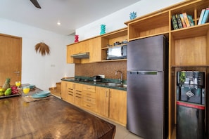 Eine moderne Küche mit Holzschränken, einem Edelstahlkühlschrank und einer Mikrowelle.