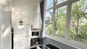 Eine kleine Küche mit Mikrowelle, Herd und Backofen. Ein Fenster bietet Blick auf Bäume.