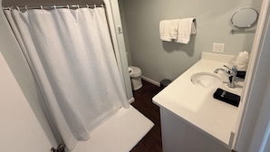 Un baño con cortina de ducha, inodoro, lavamanos y toallero.