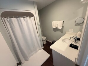Un baño con cortina de ducha, inodoro, lavamanos y toallero.