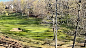 Campo de golf con búnkeres de arena, árboles y cielo despejado.