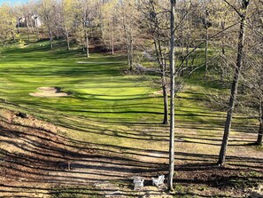 Ein Golfplatz mit Sandbunkern, Bäumen und blauem Himmel.