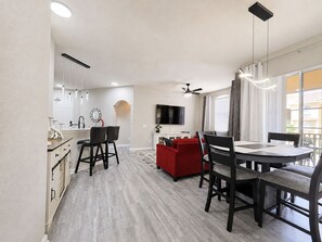 A modern living space with a dining area, kitchen, and a television. - Newly Renovated!  4-bedroom with pool near Disney and Universal Parks (Davenport)