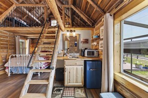 Ein Ferienhausinnenraum mit Schlafkoje, Küchenzeile und großem Fenster.
