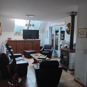 Una sala de estar con televisor, sofá, sillón y chimenea.