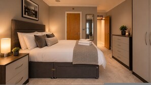 Ein Schlafzimmer mit Bett, Nachttisch, Schminktisch und einem gerahmten Bild an der Wand.