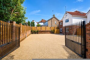A gated driveway leading to a residential area with a gravel path and a brick wall. - Cosy Modern Seconds From Shenfield Elizabeth Line (Brentwood)