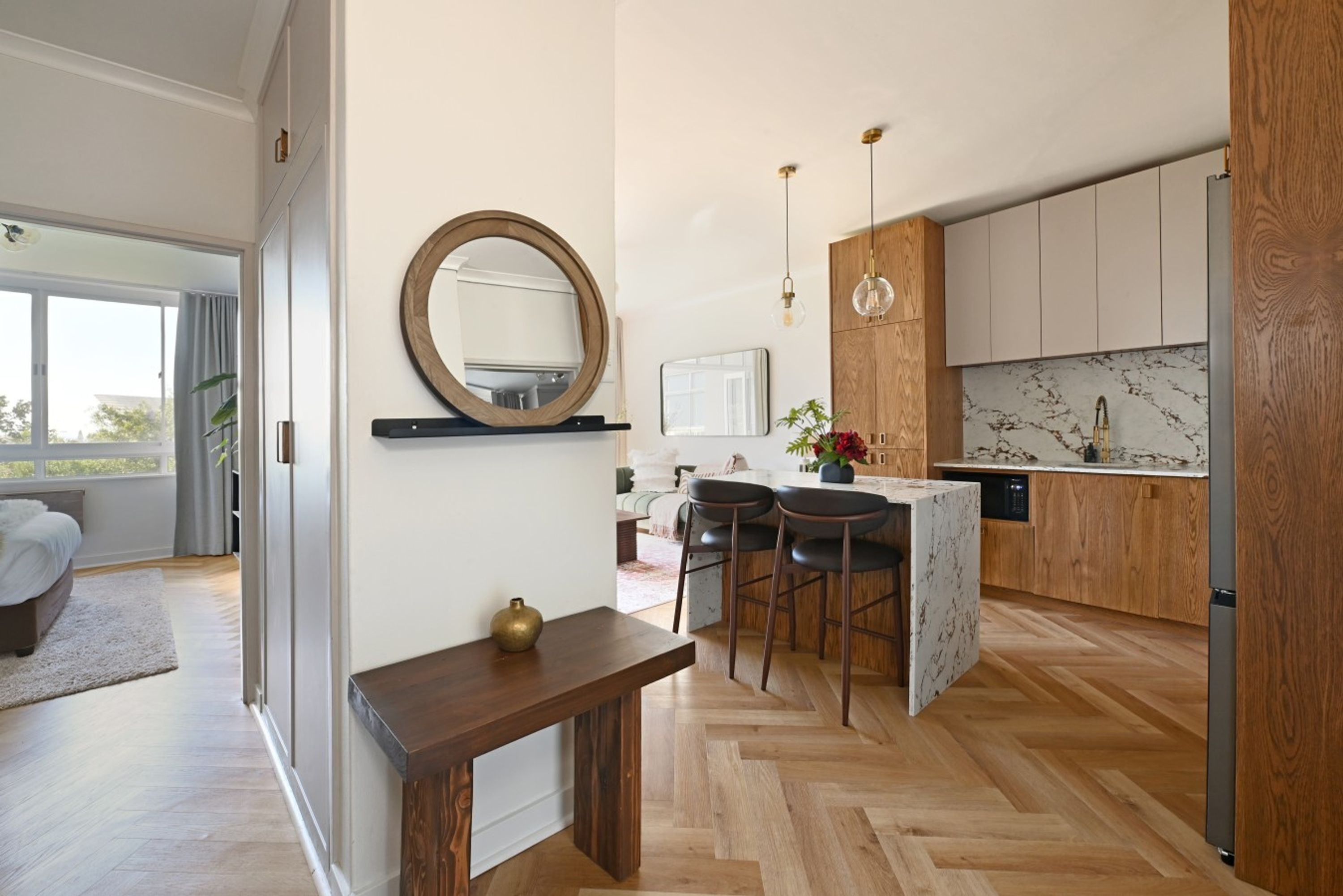 A modern kitchen with wooden cabinets, a marble backsplash, and a central island with bar stools.