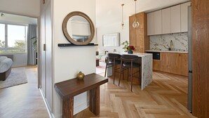Una cocina moderna con armarios de madera, salpicadero de mármol y una isla central con taburetes de bar.