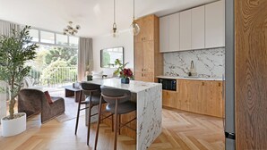 Una cocina moderna con armarios de madera, encimera de mármol e iluminación colgante.