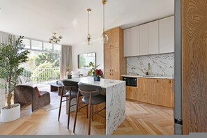 A modern kitchen with wooden cabinets, a marble countertop, and pendant lighting. - Two Bed Green Point Secure Designer Apartment (Cape Town)