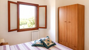Ein Schlafzimmer mit Bett, einem Fenster mit Aussicht, einem Heizkörper und einem Kleiderschrank.
